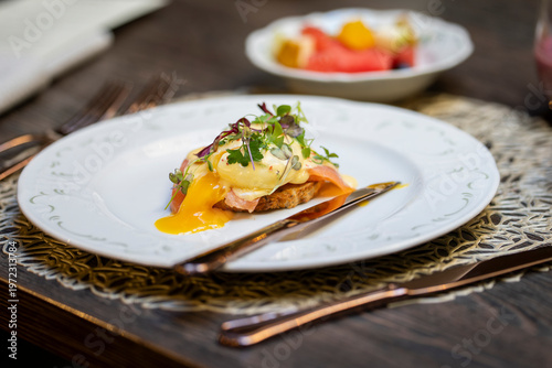 Картината върху платно Gourmet brunch dish featuring poached egg with flowing yolk, salmon and fresh herbs