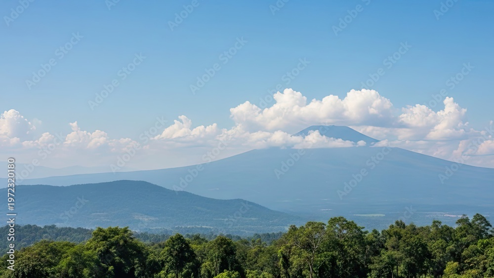 Fototapeta premium A serene mountain landscape with lush green trees under a blue sky