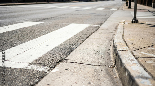 Road markings and concrete curb edge on dark asphalt pavement, high contrast street painting for urban infrastructure and traffic safety concept, industrial road surface texture.