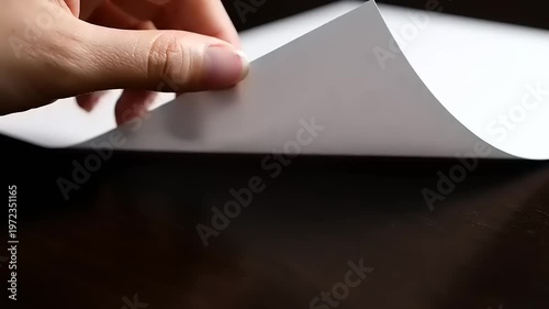 Hand holding white paper on table.