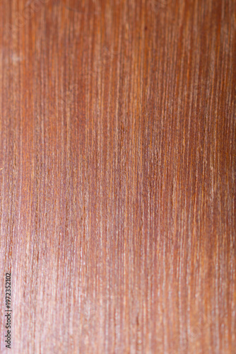 Close-up vertical macro of a smooth reddish-brown wood grain texture for interior design backgrounds conveying natural warmth.