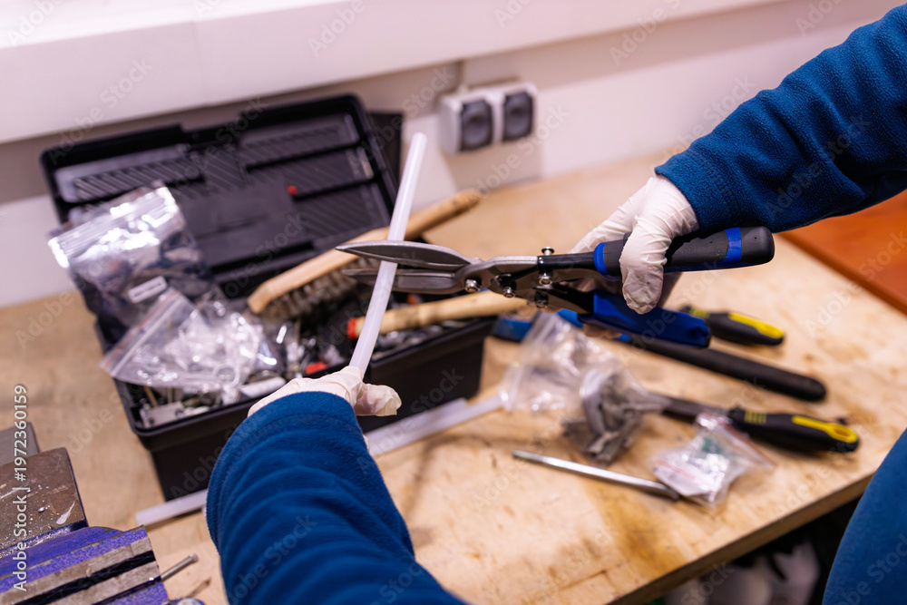 Fototapeta premium Cutting Plastic Cable Duct with Metal Shears on Workbench, Preparing Installation Material