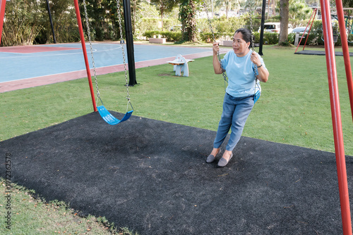 Woman swings on a swing set at a park while enjoying time outdoors during the day