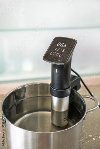 Sous vide immersion circulator heating water in pot on kitchen counter cooking process