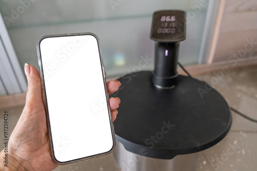 Smartphone controlling sous vide circulator on kitchen counter modern cooking technology