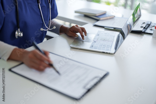 Adult medical professional working at hospital office desk managing patient data documents healthcare administration nurse doctor physician writing records