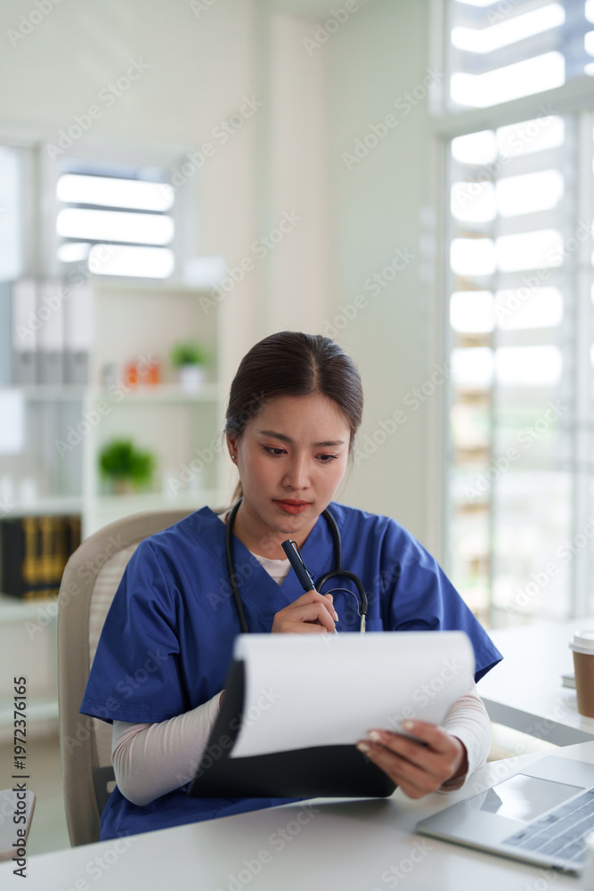 Fototapeta premium Asian adult healthcare professional woman nurse doctor focused writing patient records clinic office documents medical notes at desk workplace