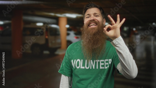 Obraz na płótnie Man with full beard in volunteer shirt makes ok sign with right hand in indoor parking building; approval