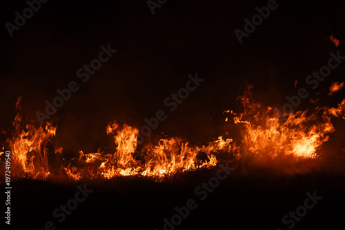 Burning fire flames isolated on dark background with smoke, dramatic wildfire effect, high contrast fire texture for overlay and design use.