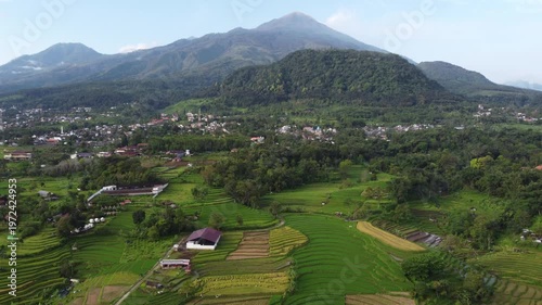 Aerial view of Mount Welirang with terraced rice fields, rural village settlement, and green valley landscape in East Java, Indonesia