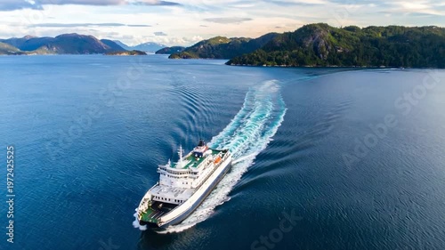 A ferry sails through a fjord, leaving a wake, with forested mountains