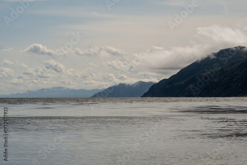 Ocean horizon with layered mountains beneath drifting clouds