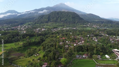 Aerial view of Mount Welirang with terraced rice fields, rural village settlement, and green valley landscape in East Java, Indonesia