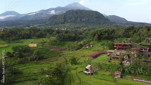 Aerial view of Mount Welirang with terraced rice fields, rural village settlement, and green valley landscape in East Java, Indonesia