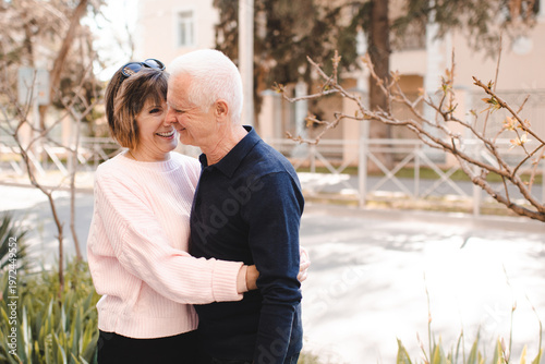 Happy senior couple 60-65 year old having fun outdoors together. Mature woman and man holding hands.