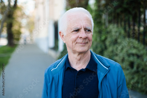 Smiling adult senior man 60-65 year old with gray hair outdoors. Close up portrait of mature person. Wellbeing lifestyle