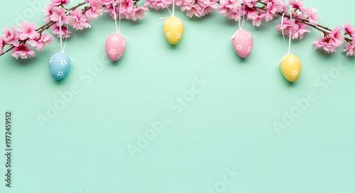 Colorful easter eggs hanging from pink flowering branches on light mint green background.