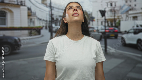 Wallpaper Mural Young woman wearing white tshirt looks up at the sky on a busy city street lined with cars and buildings; optimism. Torontodigital.ca