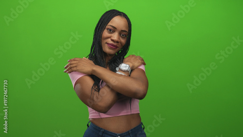 Wallpaper Mural Woman hugging arms across chest with smartwatch and pink crop top, braided hair and closed eyes in studio; self care serenity. Torontodigital.ca