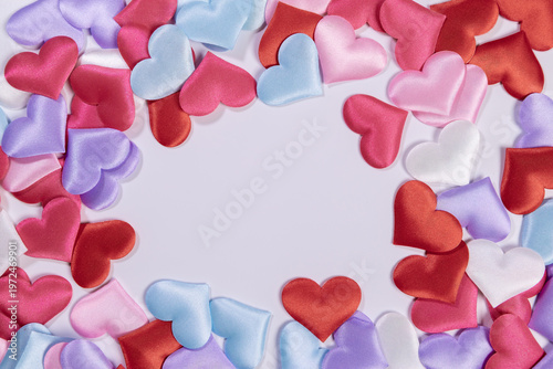 Multicolored hearts lie in a circle on a white background. Space for text.