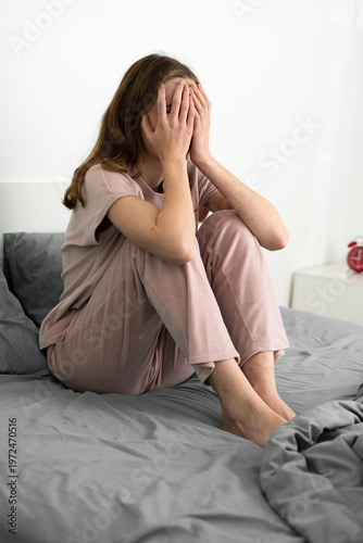 Depressed young woman crying sitting on the bed suffering from mental problem and insomnia