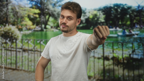 Cuadro en lienzo Man punching fist forward with bare forearm visible in street by a lake and iron railing; confidence challenge