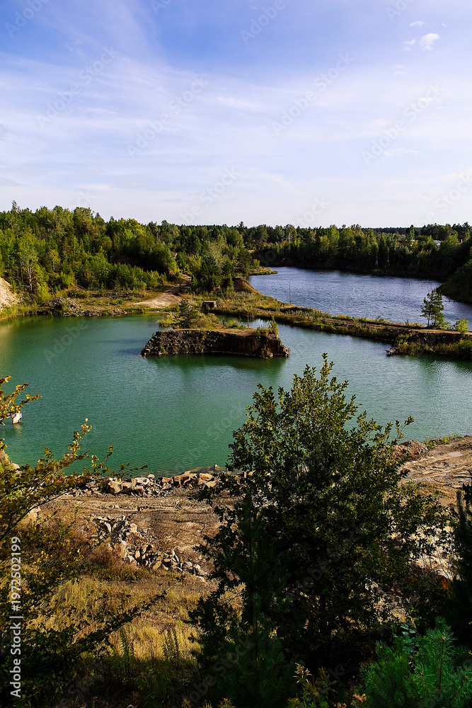 Obraz premium Old basalt quarry transformed into a lake, combining industrial geology and untouched nature scenery.