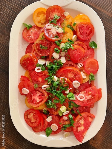 a large plate of tomatoes, sliced ​​tomatoes, juicy tomato slices, tomato salad sprinkled with green onions