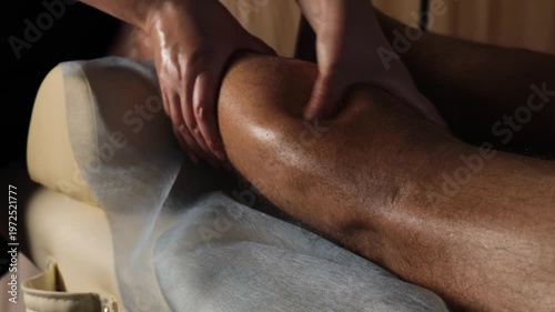 Therapist massaging male calf muscle with deep pressure for sports injury recovery