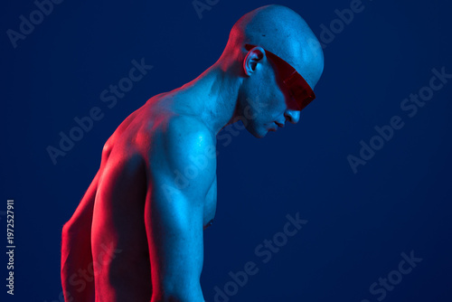 Man with sunglasses in vibrant blue and red lighting, creating a striking contrast and showcasing a modern aesthetic. A captivating portrayal of contemporary art trends.