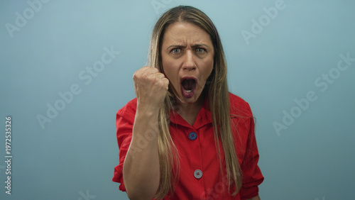 Cuadro en lienzo Woman shouting with clenched fist and furrowed brow against light blue backdrop in studio; anger defiance empowerment resilience