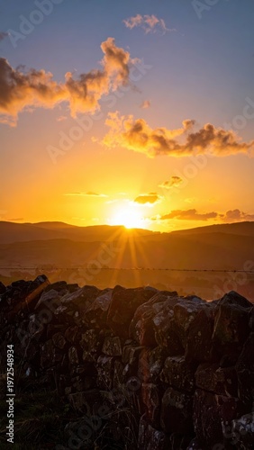 Serene Sunset Over Hills with Dramatic Clouds and Warm Glow