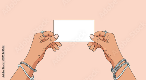 Two hands adorned with silver rings and bracelets hold a blank white business card against a peach background for professional networking and contact info.