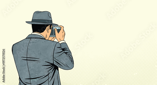 Back view of a man wearing a grey suit and fedora hat while taking a photograph with a classic rangefinder camera.