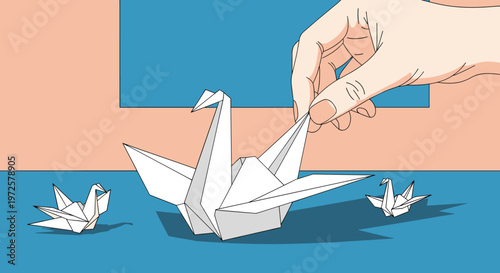 Human hand carefully folding a white paper origami swan on a blue and salmon background illustrates creativity and the traditional japanese art of paper folding.