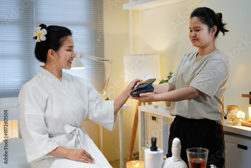 Healthcare time. Closeup on female massage therapist in massage cabinet with client accepting credit card payments via terminal at massage room
