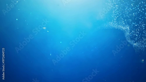 A blue ocean with a lot of bubbles. The bubbles are scattered all over the ocean. The ocean is very clear