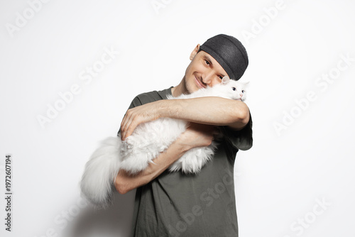 Happy young man hugging white cat isolated on white background.