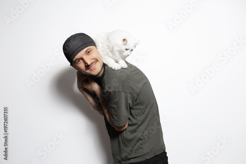 Happy young man playing with white cat isolated on white background.