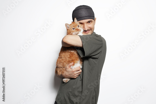 Happy young man hugging red-white cat isolated on white background.