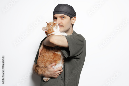Happy young man hugging red-white cat isolated on white background.