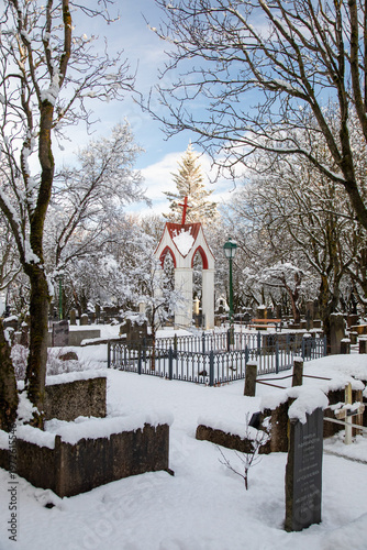 Sun on pagoda house in in snowy Holvallagardur cemetery Reykjavik