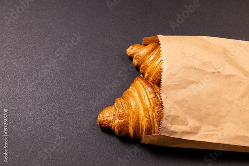 Freshly baked croissants peeking from a brown paper bag