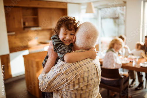 Grandfather hugging grandson during family meal at home