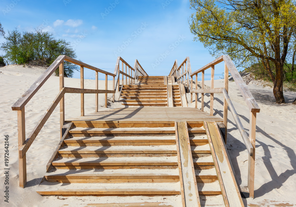 Obraz premium Wooden staircase leading through a sand dune to the sea