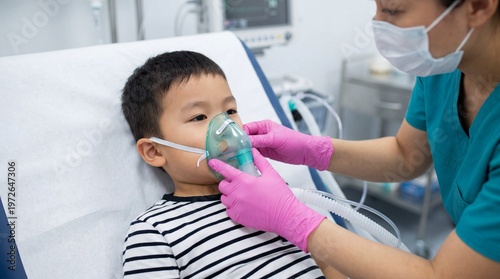 Female nurse in pink gloves placing a green oxygen mask on a young Asian boy in a hospital room, pediatric respiratory care, medical clinic.