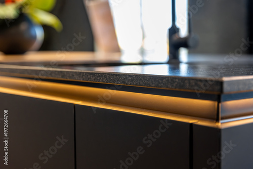 Kitchen cabinet LED lighting dark fronts modern minimal design. Furniture detail close up.