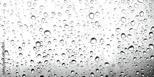 A close up view of clear raindrops scattered across a smooth glass surface in black and white