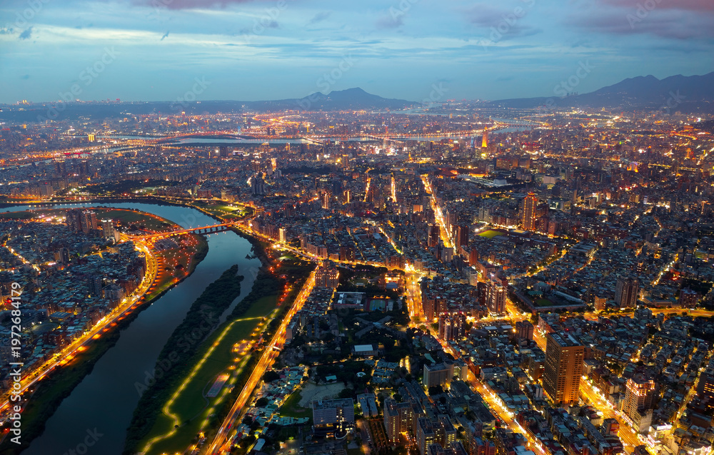 Obraz premium Aerial night skyline of Taipei City, with a view of Xindian River winding thru downtown, 101 Tower standing out amid crowded buildings in Xinyi Commercial District and city lights glowing at blue dusk