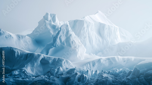 Towering Arctic glacier formations with textured blue ice base and bright white snow peaks rising under soft misty pale sky. Pristine polar wilderness, cold climate dramatic nature panorama.